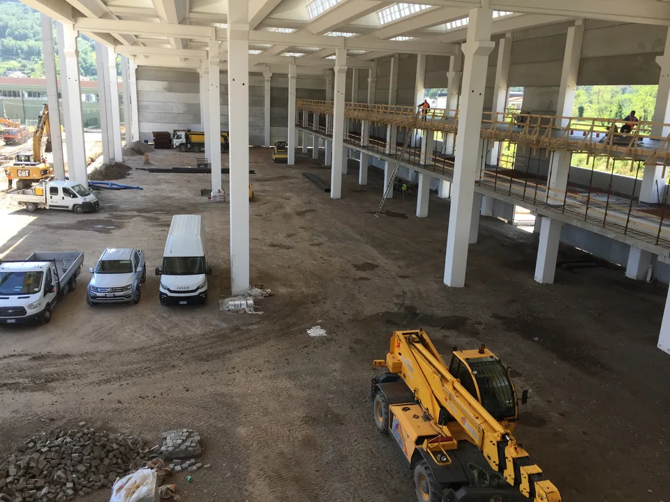 Cantiere di un capannone in costruzione con i furgoni e i mezzi sul fondo